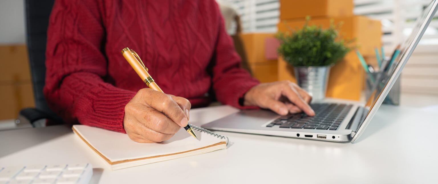 Woman writing notes from laptop