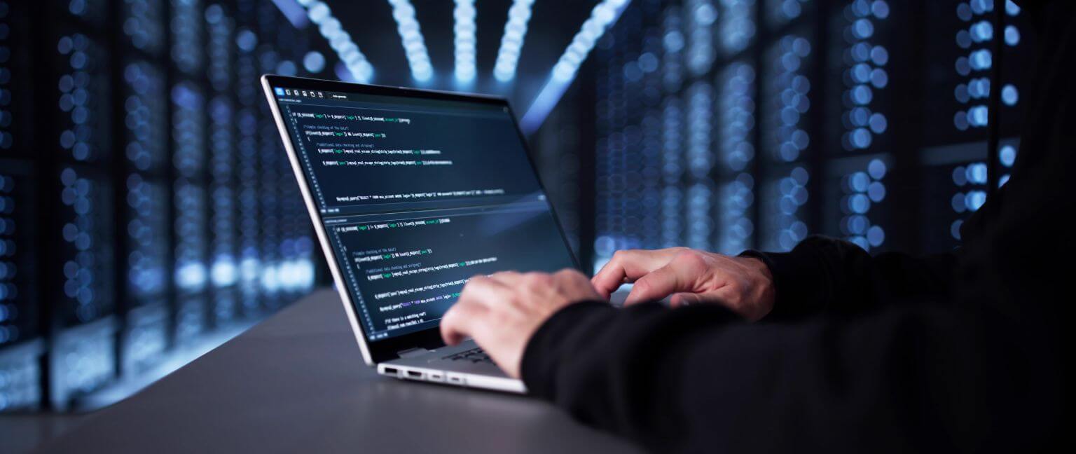 Hacker typing on a laptop