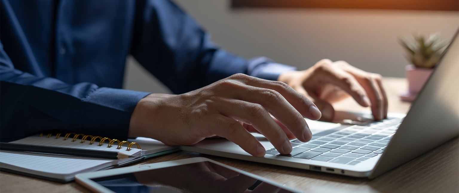 close-up of gentleman typing on laptop